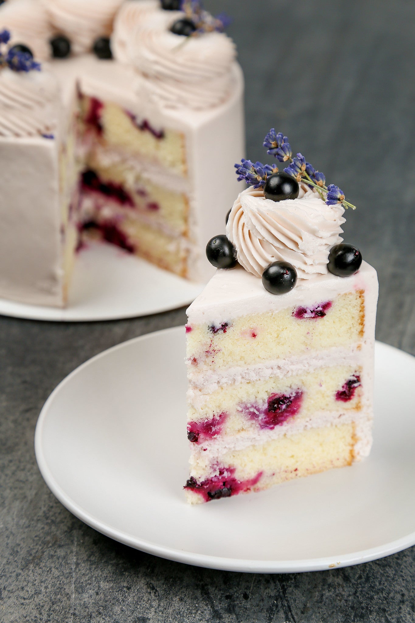 A piece of white sponge cake with berries and white cream, decorated with whipped cream and blackcurrant - KICA books